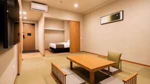 A compact hotel room with a bed, a wooden table, and a sofa. - Randor Residential Hotel Kyoto Suites (Kyoto)
