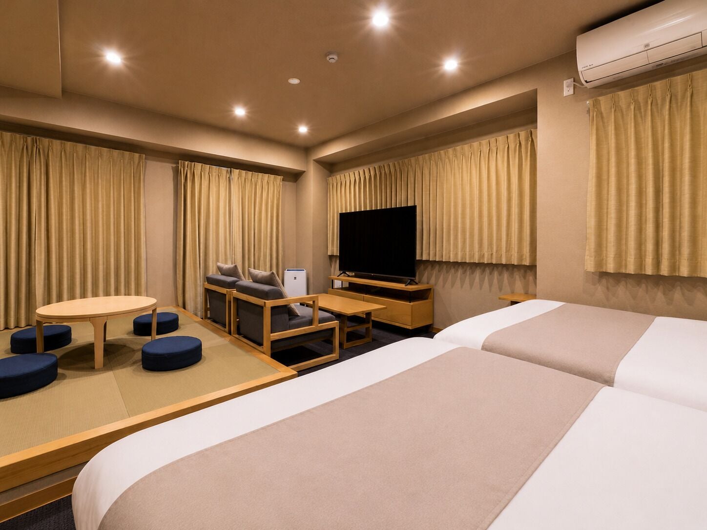 Une chambre d’hôtel avec deux lits, une télévision, une petite table et un coin salon.