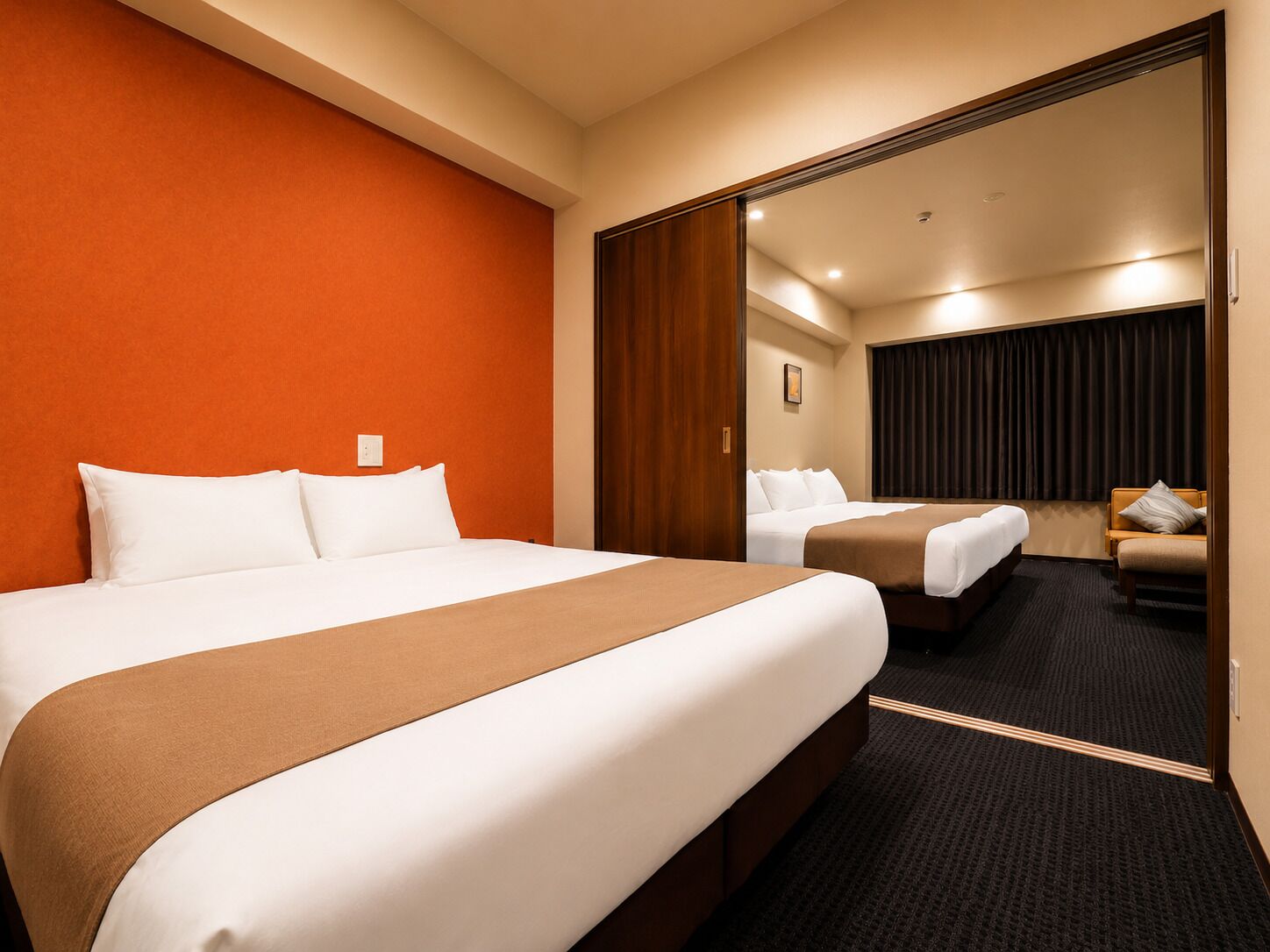 Ein Hotelzimmer mit einem großen Bett, einem kleineren Bett, einem Spiegel und einem dunklen Teppich.