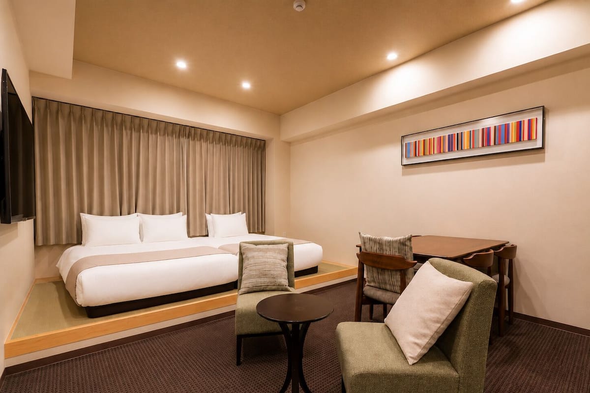 A hotel room with a bed, a sofa, a small table, and a TV.