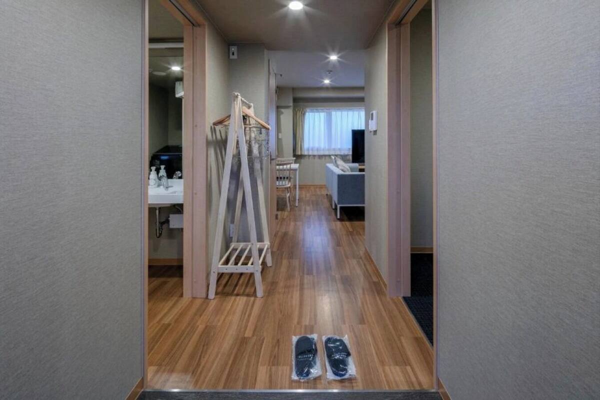 A hotel room with a wooden floor, a bed, a desk, and a chair.