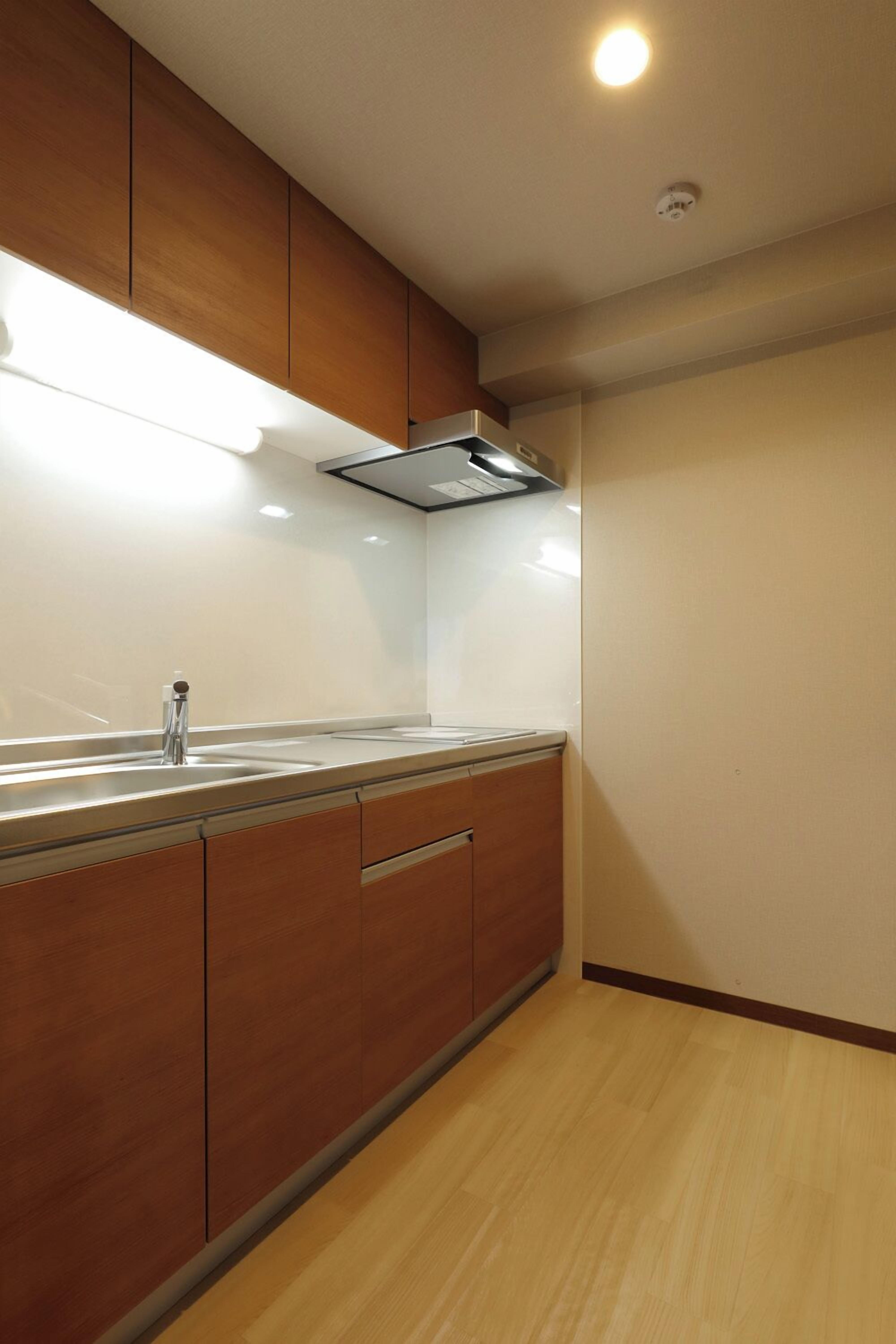 A modern kitchen with wooden cabinets, a stainless steel sink, and under-cabinet lighting.
