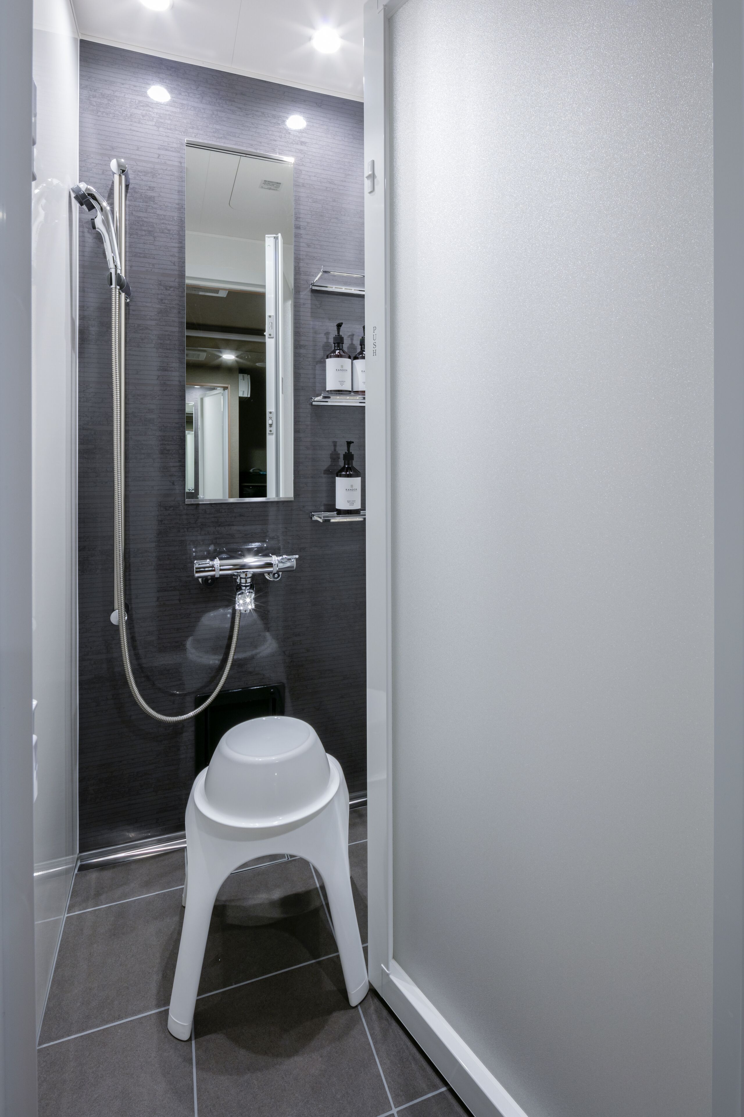 A modern bathroom with a walk-in shower, a white pedestal sink, and a mirror above the sink.