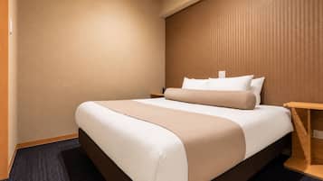A hotel room with a bed, a nightstand, and a wooden side table.