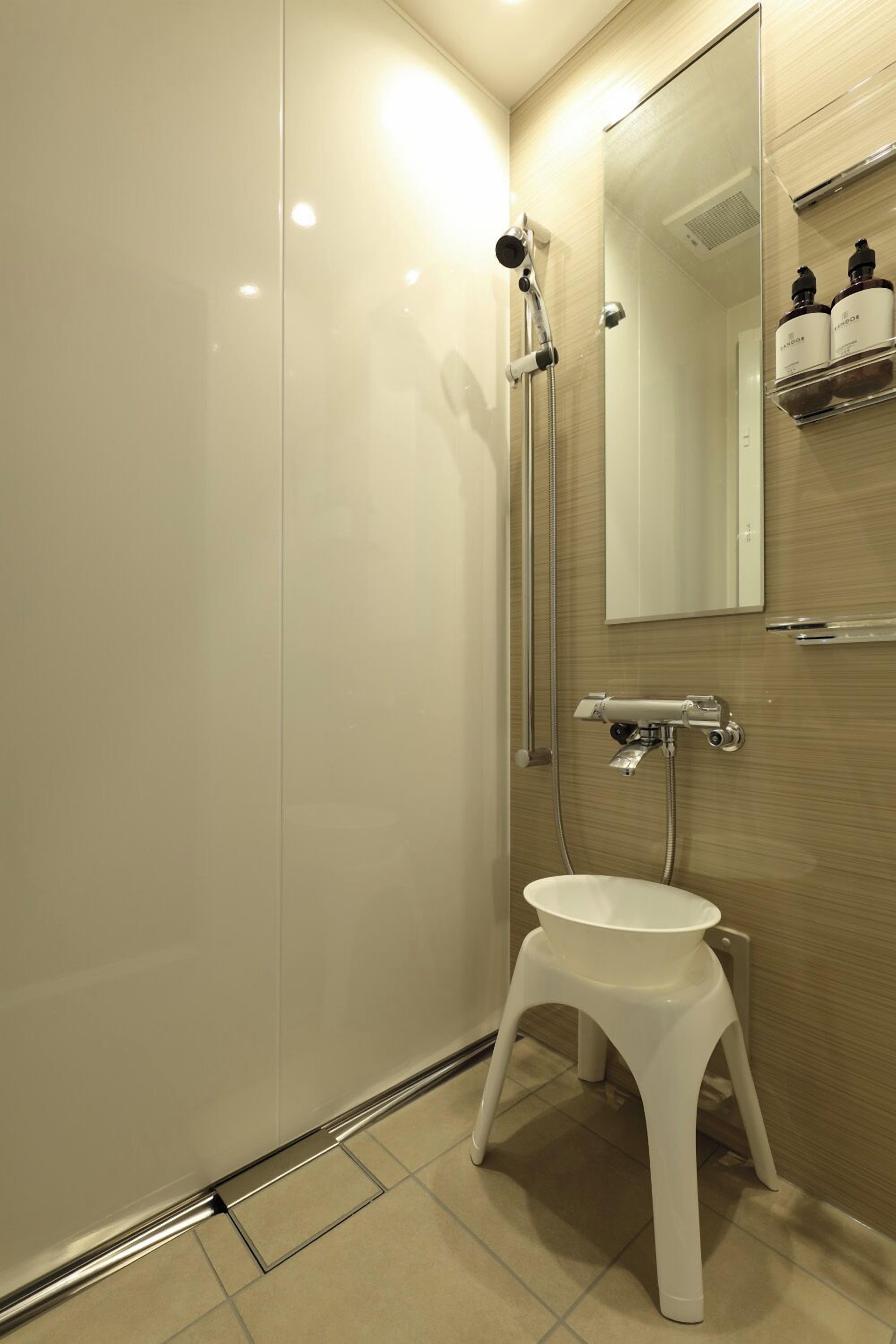 A modern bathroom with a glass shower enclosure, a white pedestal sink, and a mirror above the sink.
