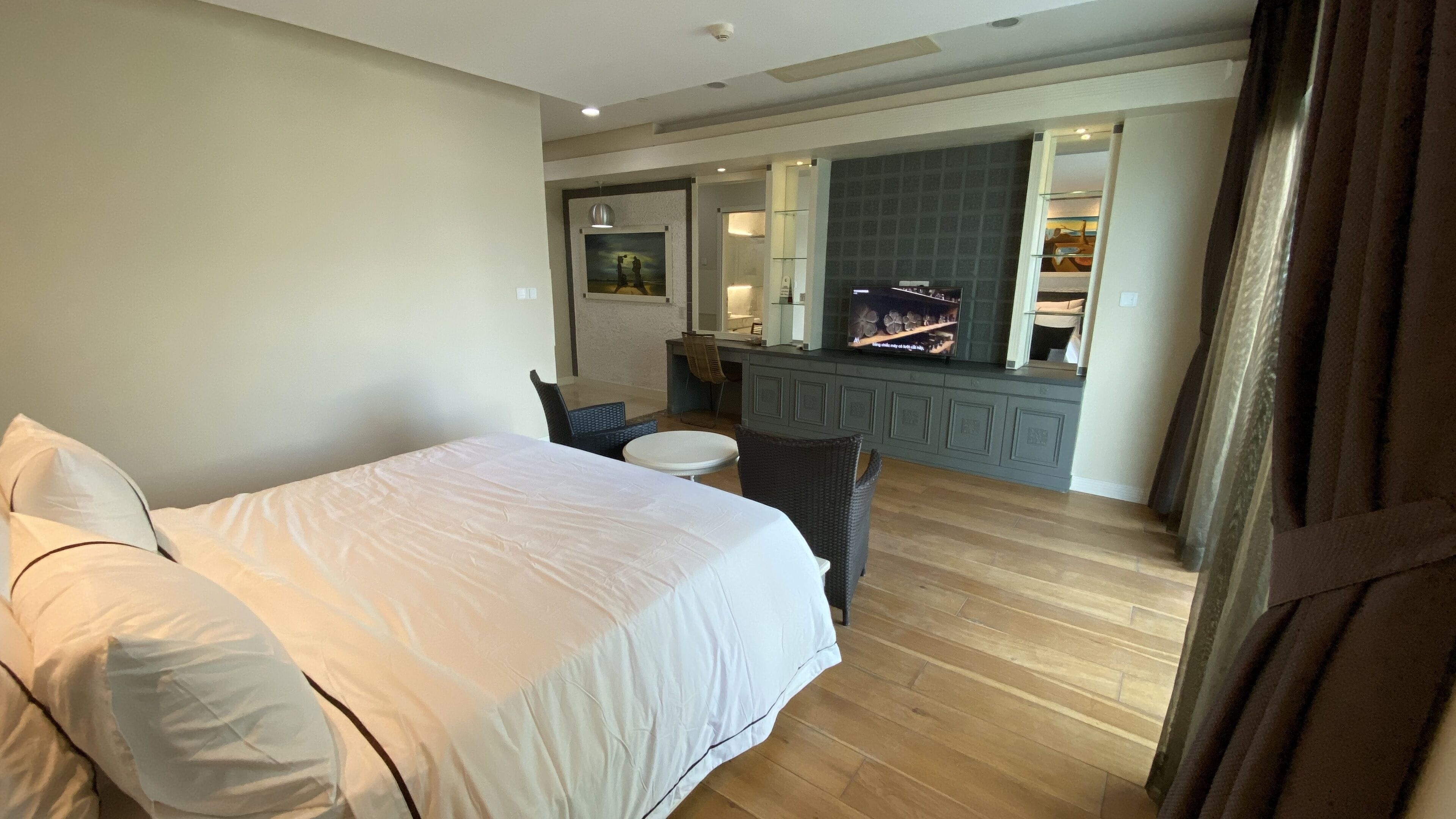 Una habitación de hotel con una cama, una mesita redonda pequeña, una silla, un escritorio con computadora y un televisor.