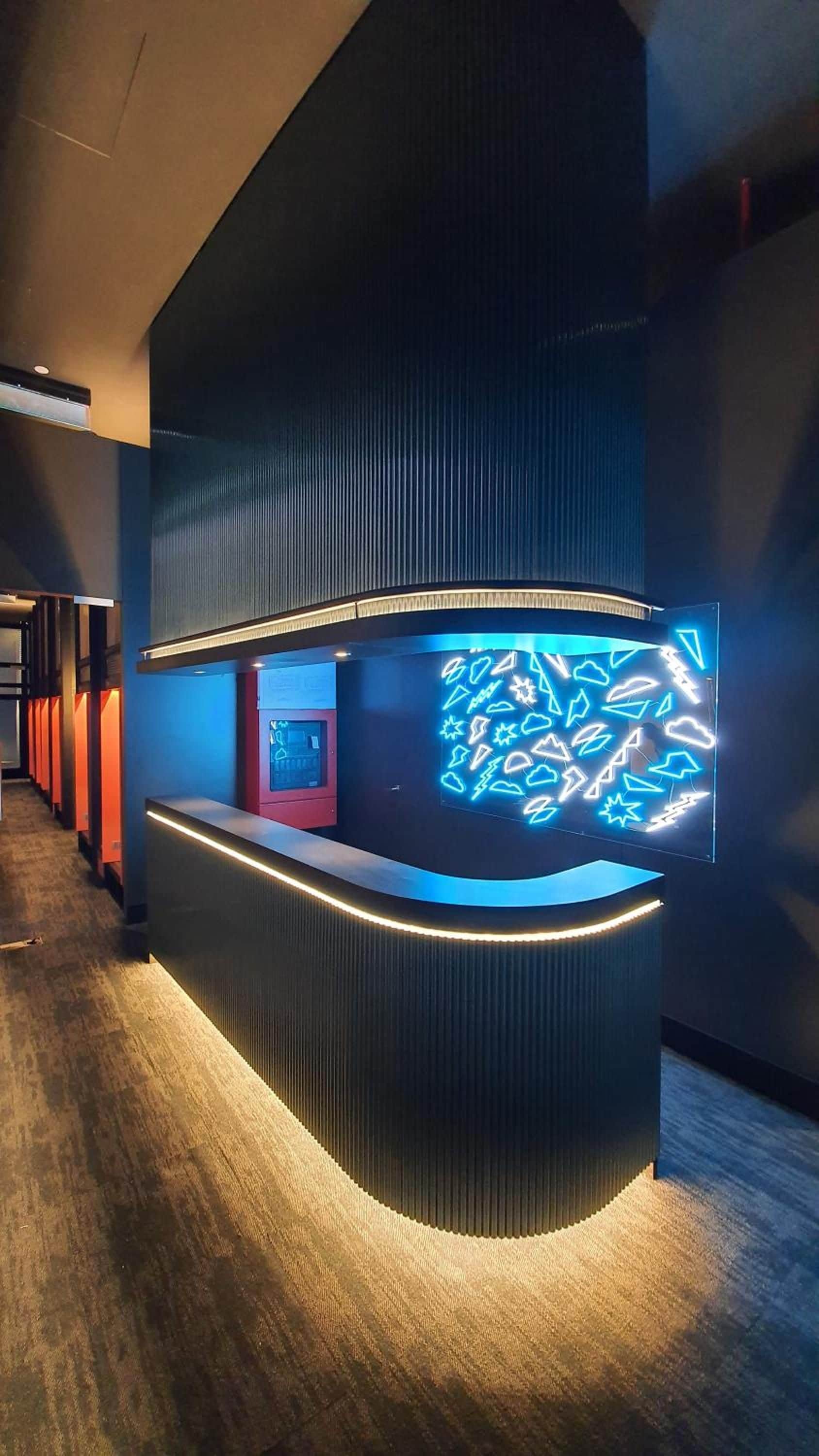 A reception desk with a modern design, a digital display, and a patterned light installation.