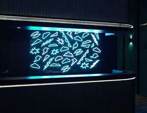 A modern reception area with a digital display featuring various geometric shapes and symbols. - Capsule Transit KLIA2 Airside (Sepang)