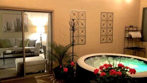 Un salon chaleureux avec un canapé, une table basse, un jacuzzi agrémenté de fleurs rouges et des œuvres d’art décoratives accrochées au mur.