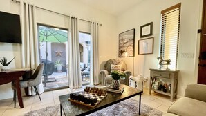 Un salon comprenant une table basse, un canapé et un coin repas avec des chaises. Une porte-fenêtre coulissante donne accès à un espace extérieur.