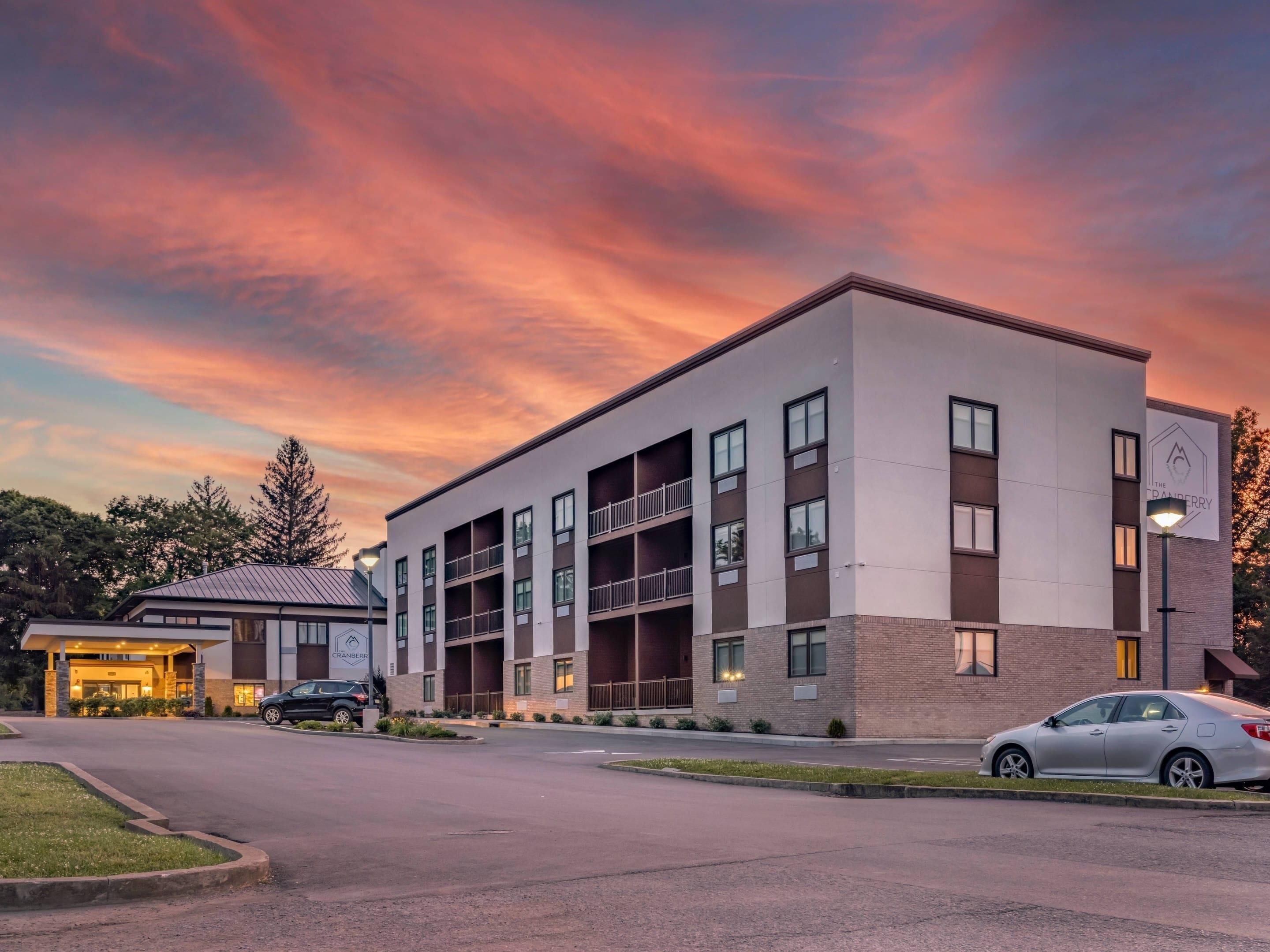 A multi-story hotel with a modern architectural design, featuring a flat roof and a mix of brick and concrete exterior.