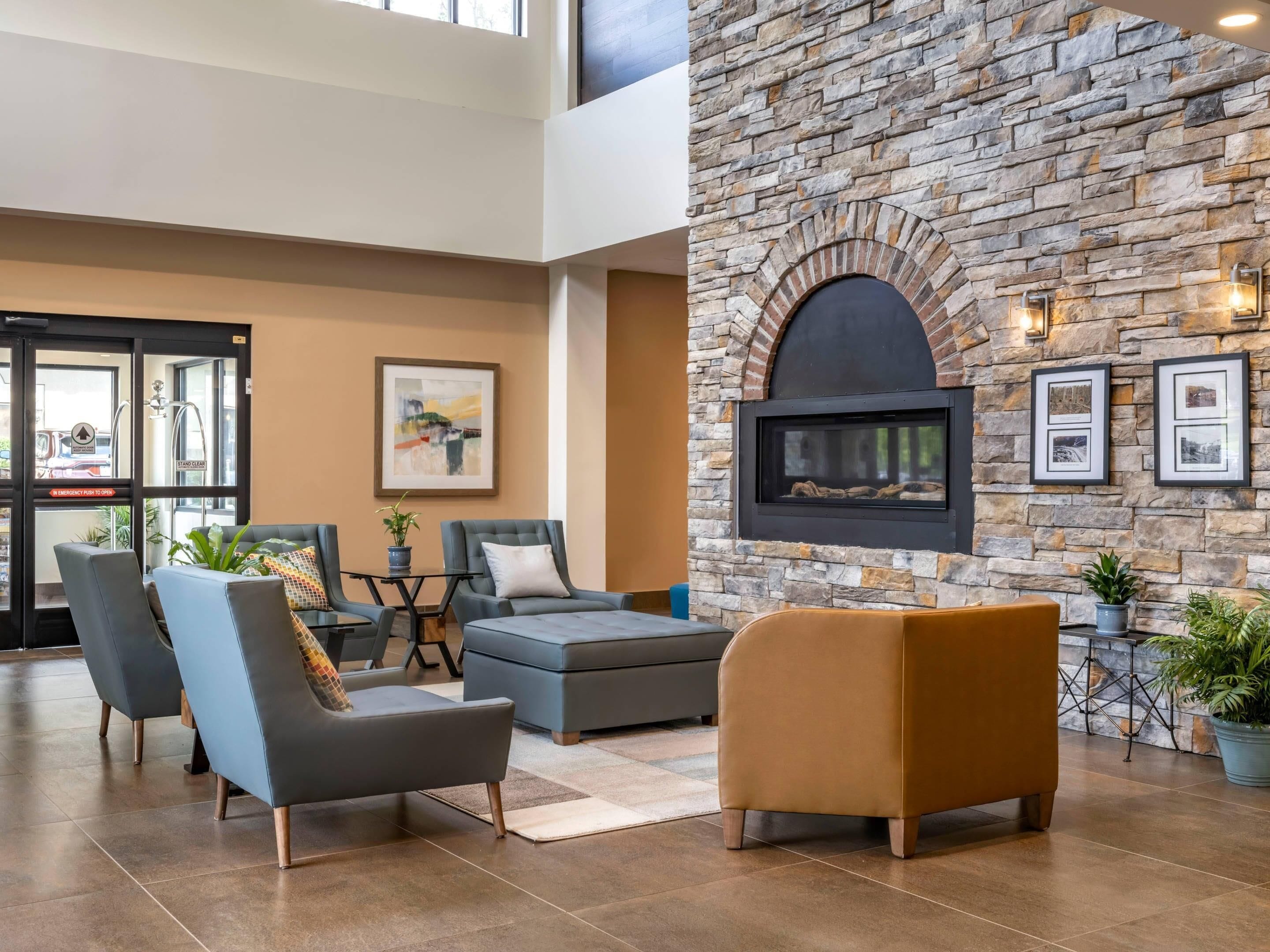 A lobby with a stone wall, a fireplace, and seating areas.