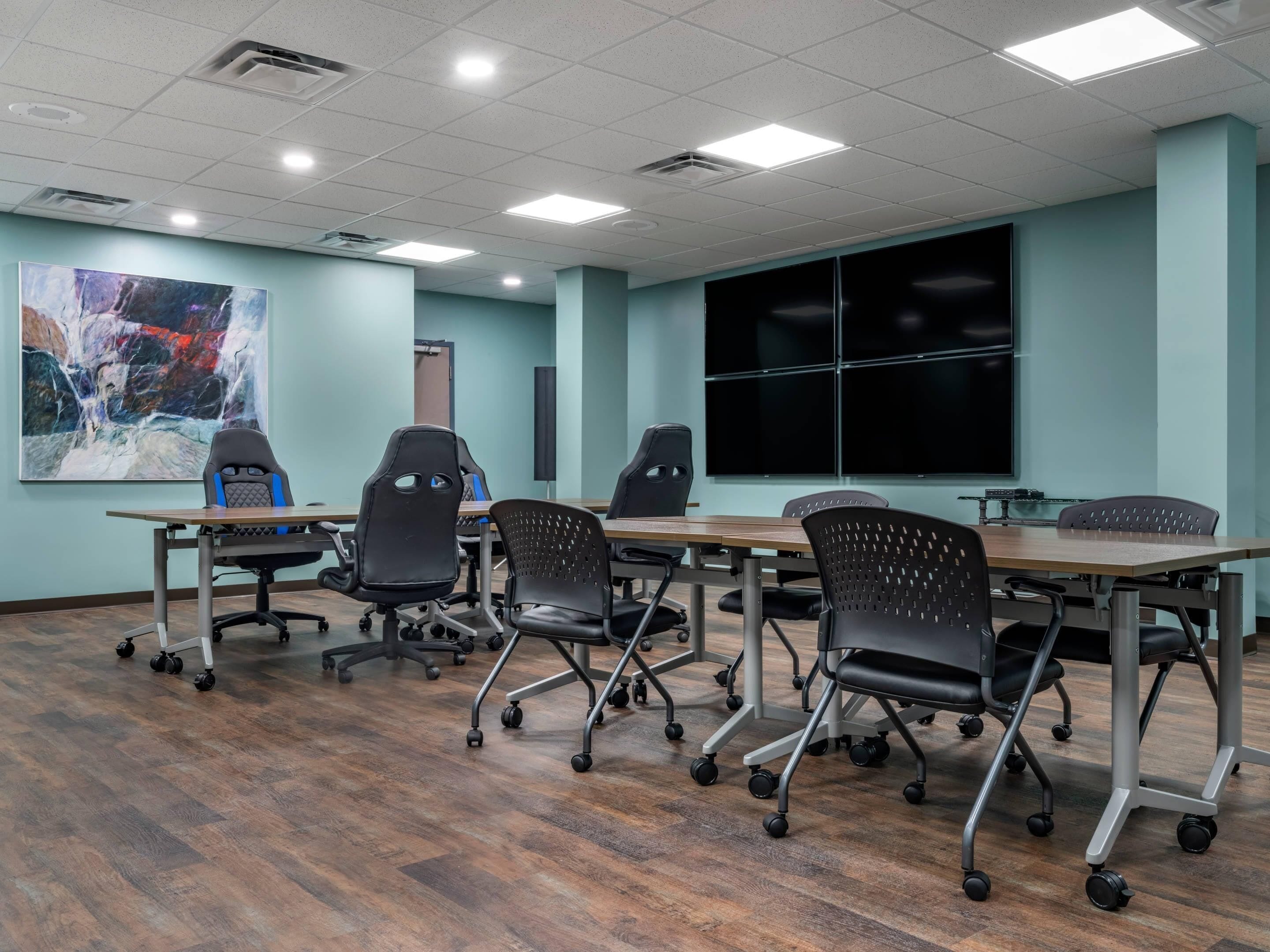 A conference room with a large table, multiple chairs, and a large abstract painting on the wall.