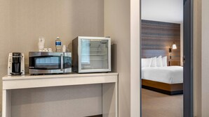 A hotel room with a bed, a desk with a microwave, a coffee maker, and a bottle of water. - The Cranberry, an Ascend Collection Hotel (Morgantown)