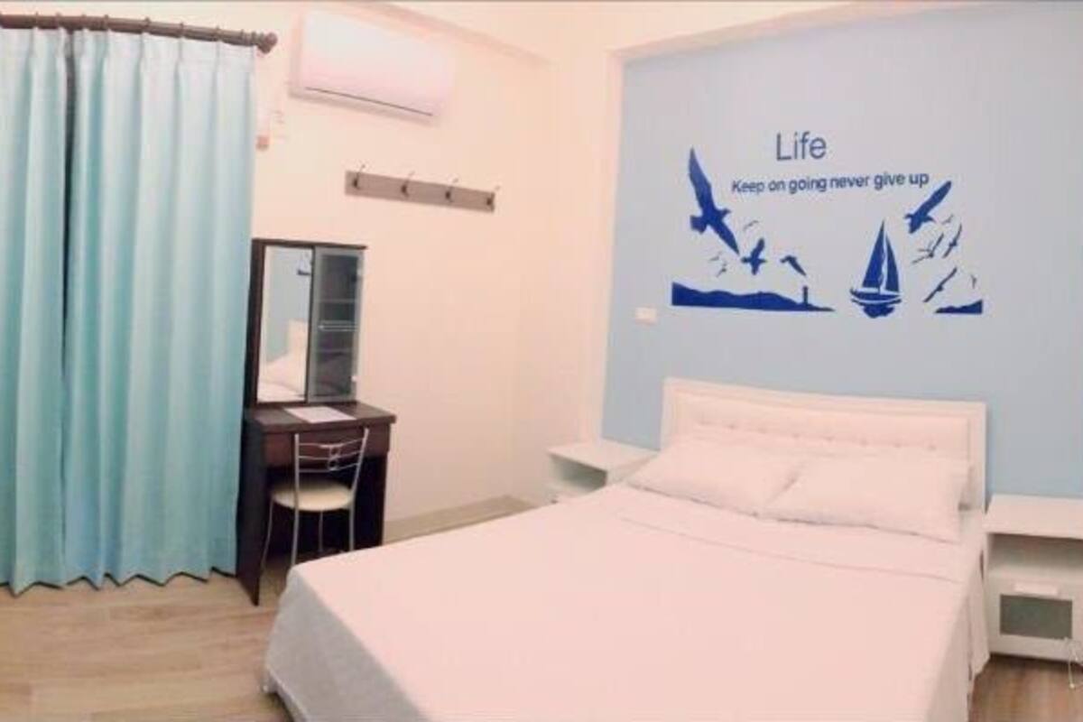 A hotel room with a bed, a desk, a TV, and a window with curtains.