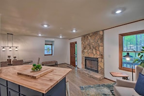 A modern kitchen with a large island, a stone fireplace, and a view of the outdoors.