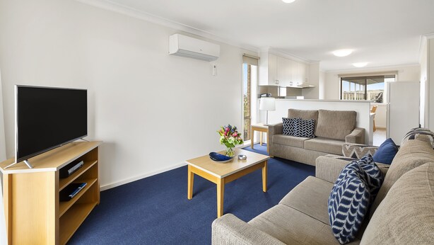 A living room with a flat-screen TV, a coffee table, and a sofa.