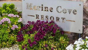A sign for Marine Cove Resort surrounded by vibrant flowers.