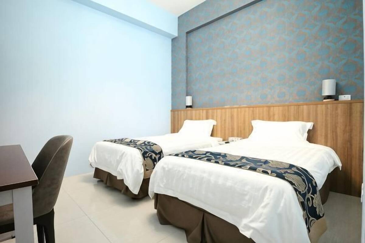 Habitación de hotel con dos camas, un escritorio y una silla.
