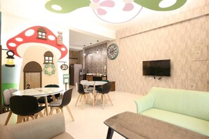 A modern living room with a round glass table, black chairs, a green sofa, and a kitchen area in the background. - Mushroom 30 (Taitung)