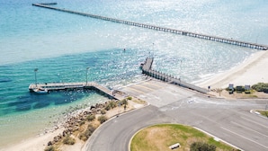 An aerial view of a coastal road with a pier extending into the sea. - Whitecliffs Beach Resort (Rye)