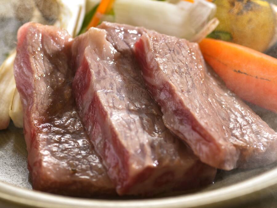 A plate with raw beef, vegetables, and a white item, possibly a dumpling or bread.