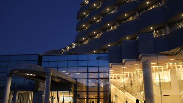 A modern hotel with multiple balconies, large glass windows, and a prominent entrance with an escalator. - The Grand Resort Princess Arima (Kobe)