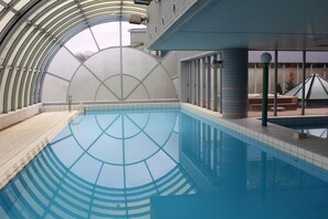 An indoor swimming pool with a glass ceiling, tiled walls, and a bench area. - The Grand Resort Princess Arima (Kobe)