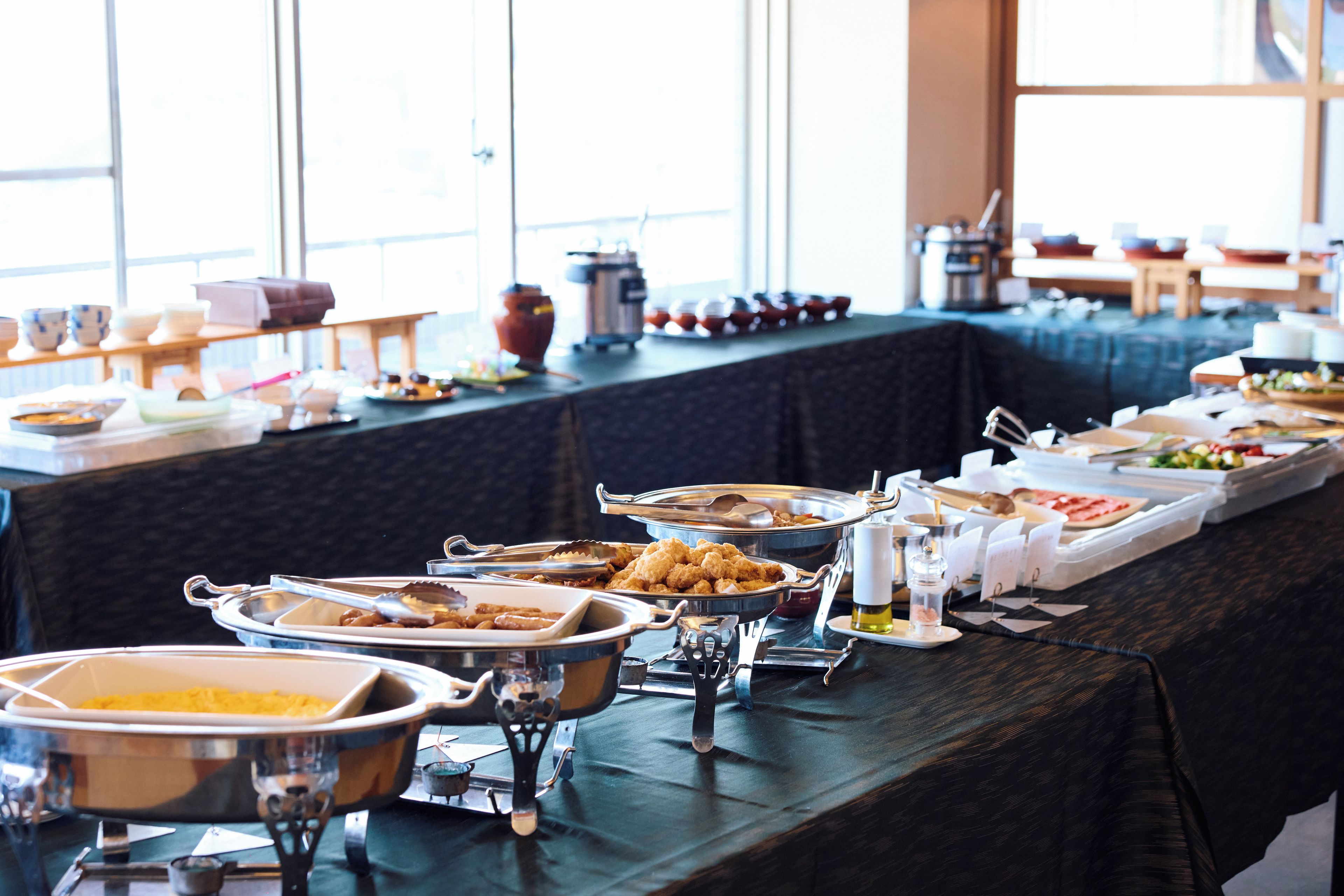 A buffet table with various food containers and utensils.