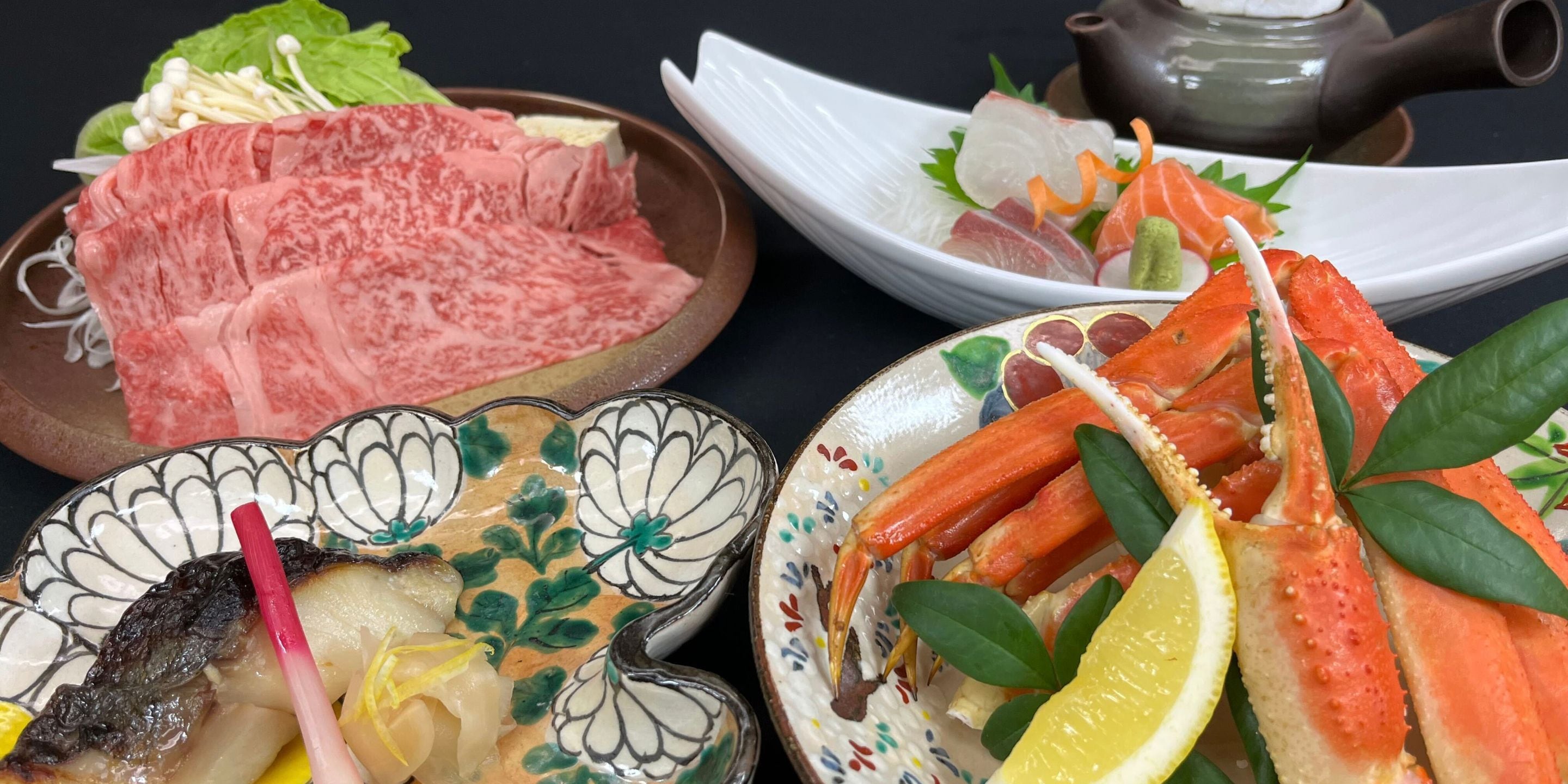 A variety of seafood dishes on plates, a teapot, and a decorative ceramic bowl.