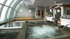 A spa area with a hot tub, seating, and a stone wall. - The Grand Resort Princess Arima (Kobe)