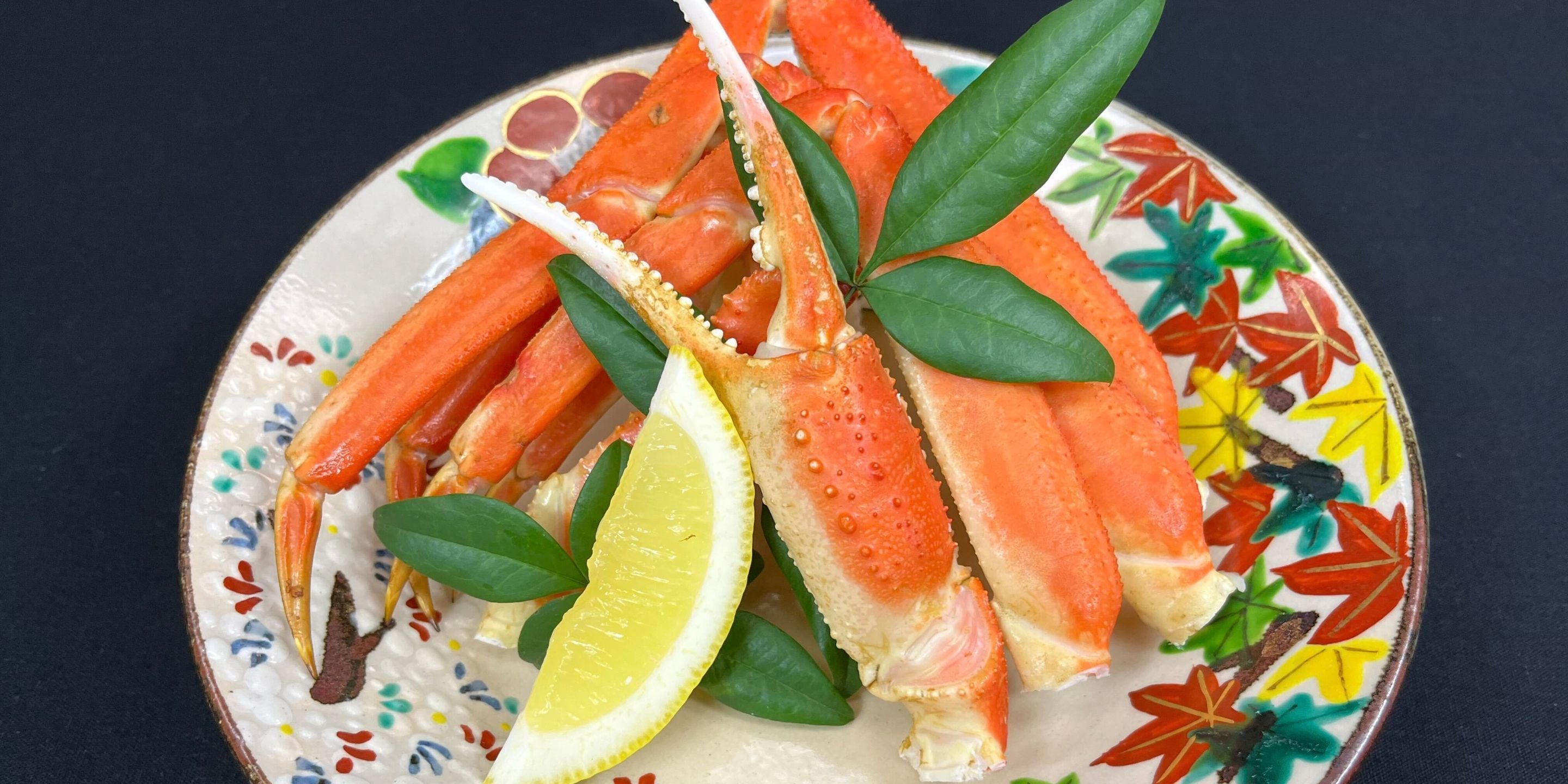 Un plato con patas de cangrejo, limón y hojas verdes.