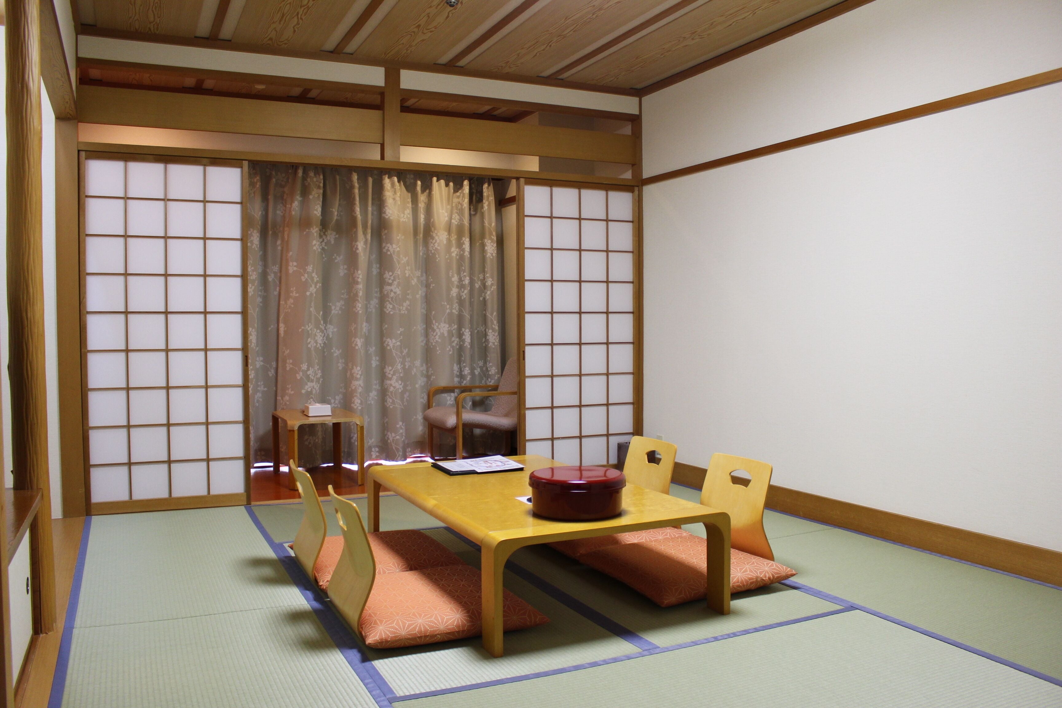 A traditional Japanese room with tatami flooring, a low table with cushions, and sliding doors.