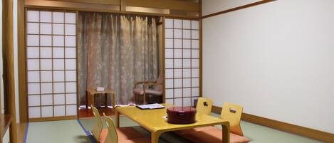 A traditional Japanese room with tatami flooring, a low table with cushions, and sliding doors.