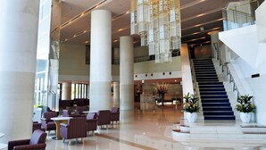 A spacious lobby with high ceilings, large columns, and a staircase leading to upper floors. - The Grand Resort Princess Arima (Kobe)