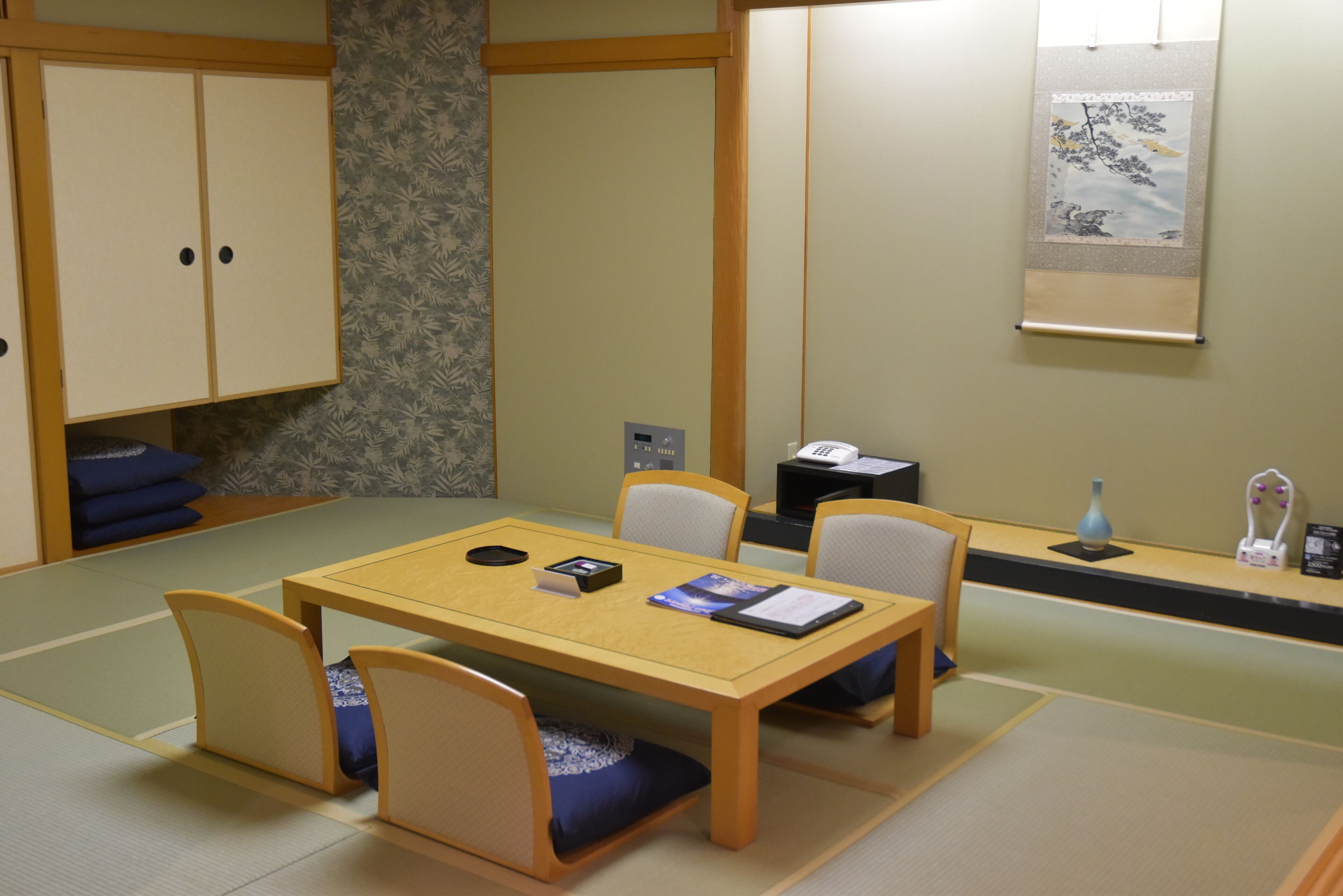 A traditional Japanese room with tatami flooring, a low table, and four chairs.