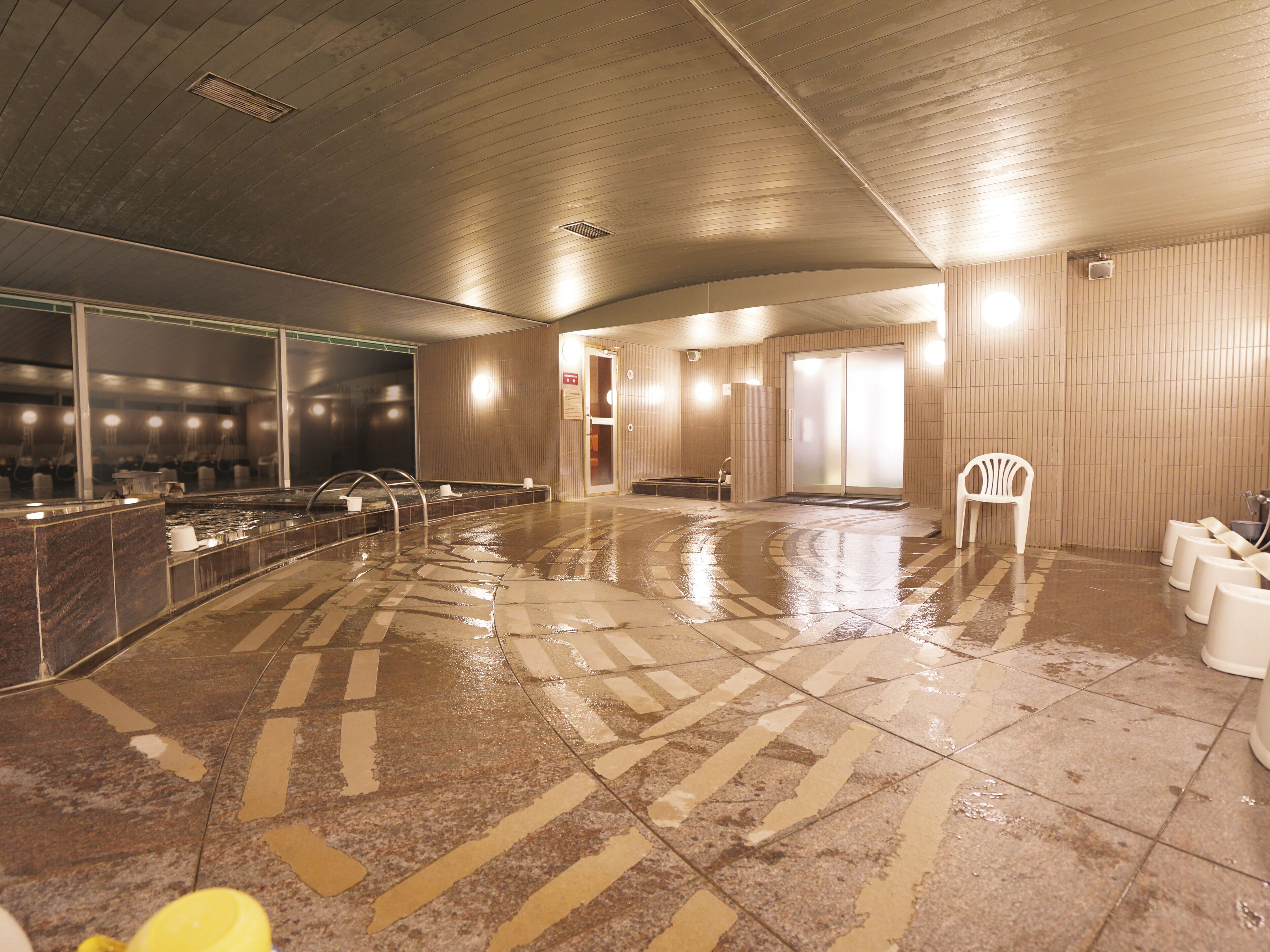 A wet floor in a public indoor space with a counter, chairs, and a door.