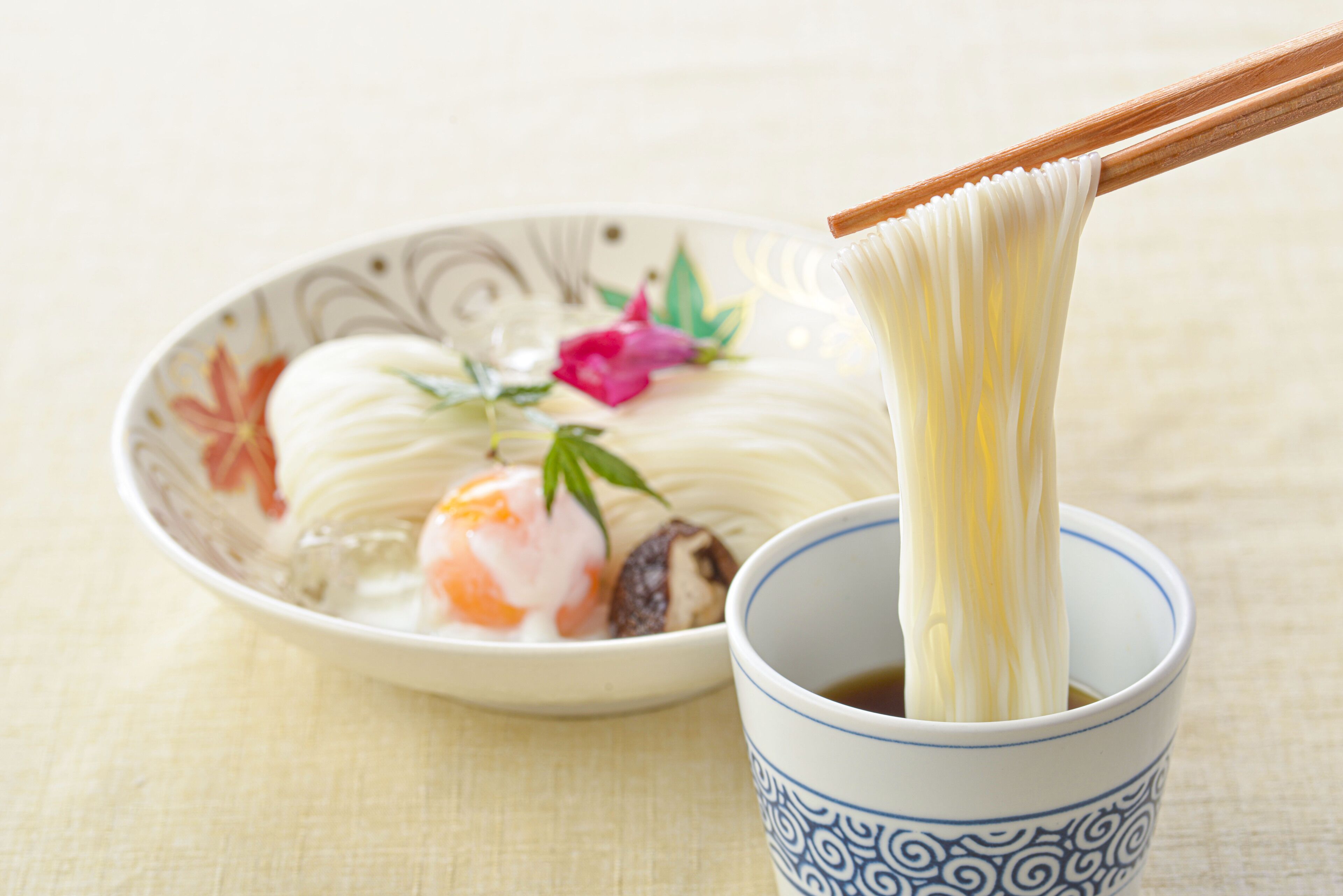 Eine Schüssel Ramen mit Nudeln, die mit Stäbchen angehoben werden.