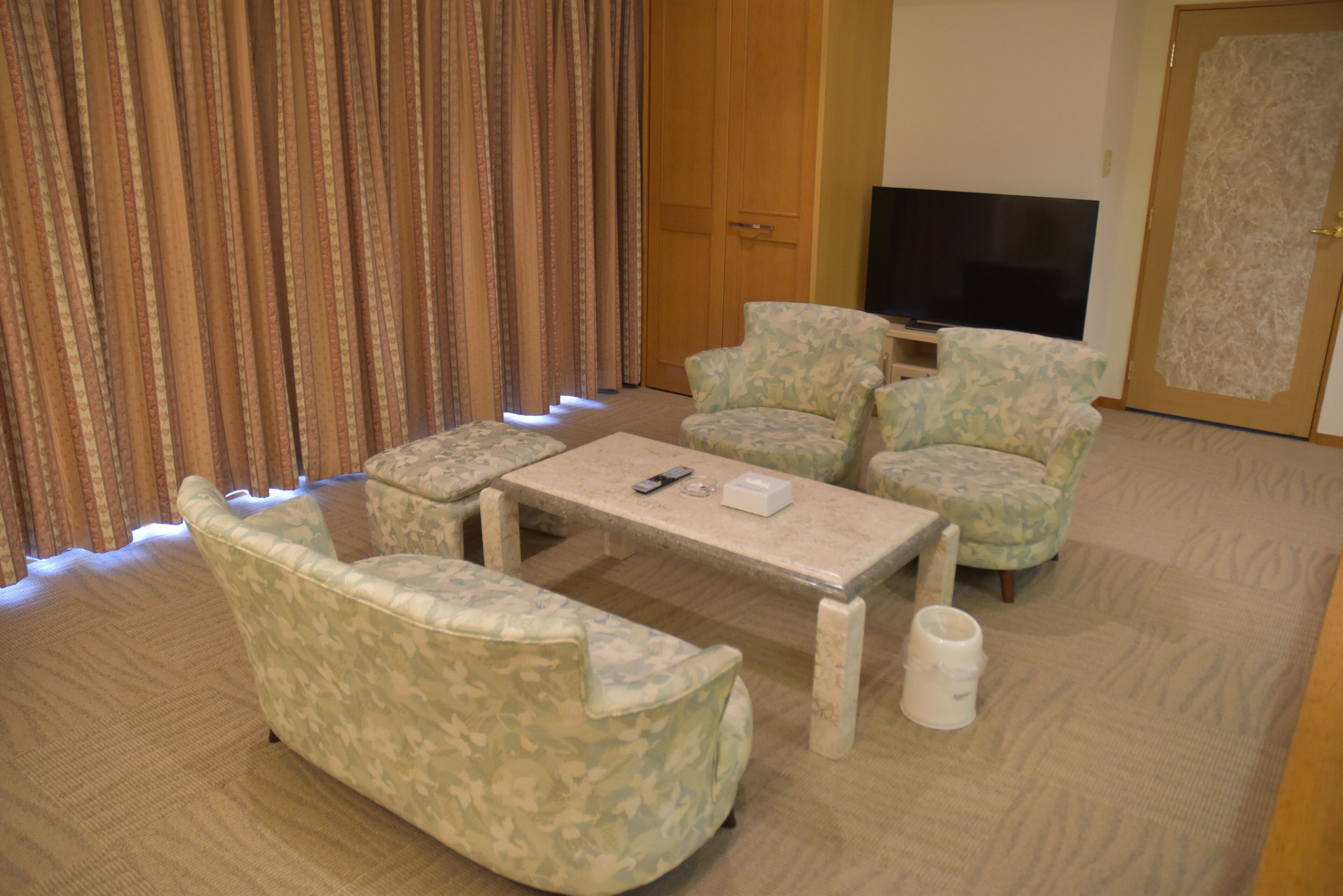 A living room with a sofa, two armchairs, a coffee table, and a television.