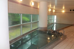 Une piscine avec des parois en verre transparent, un sol carrelé et une colonne au centre.