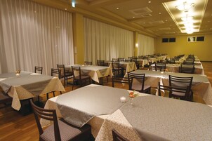Un salón de banquetes con varias mesas dispuestas para comer, organizadas en filas.