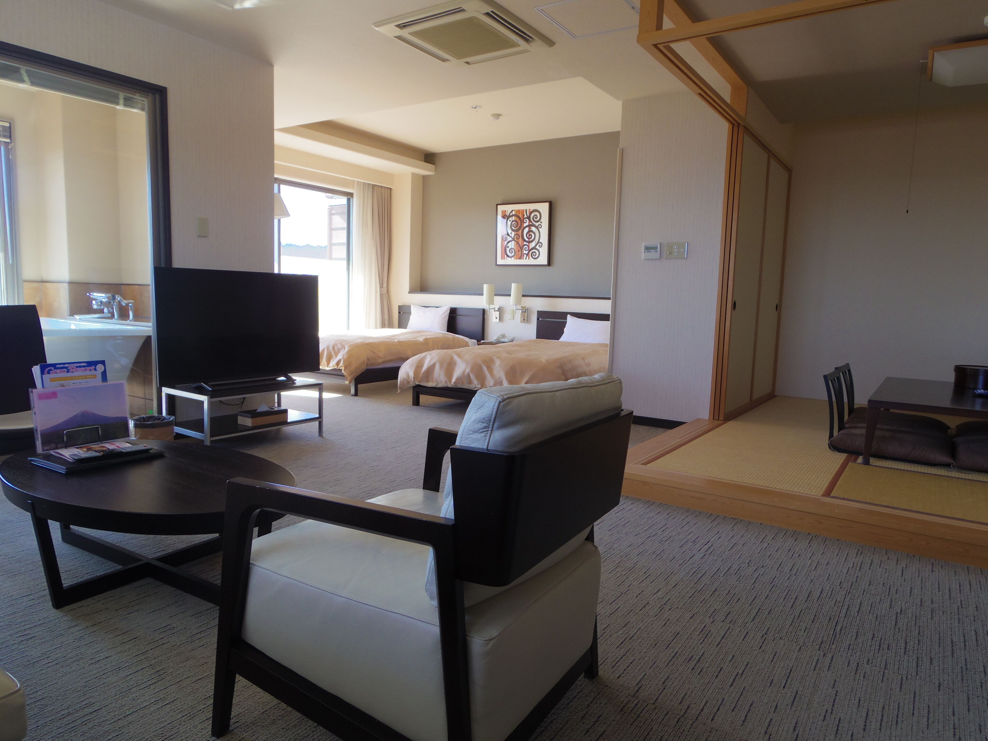 A hotel room with a bed, a desk, a chair, a television, and a window.