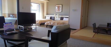 A hotel room with a bed, a desk, a chair, a television, and a window.
