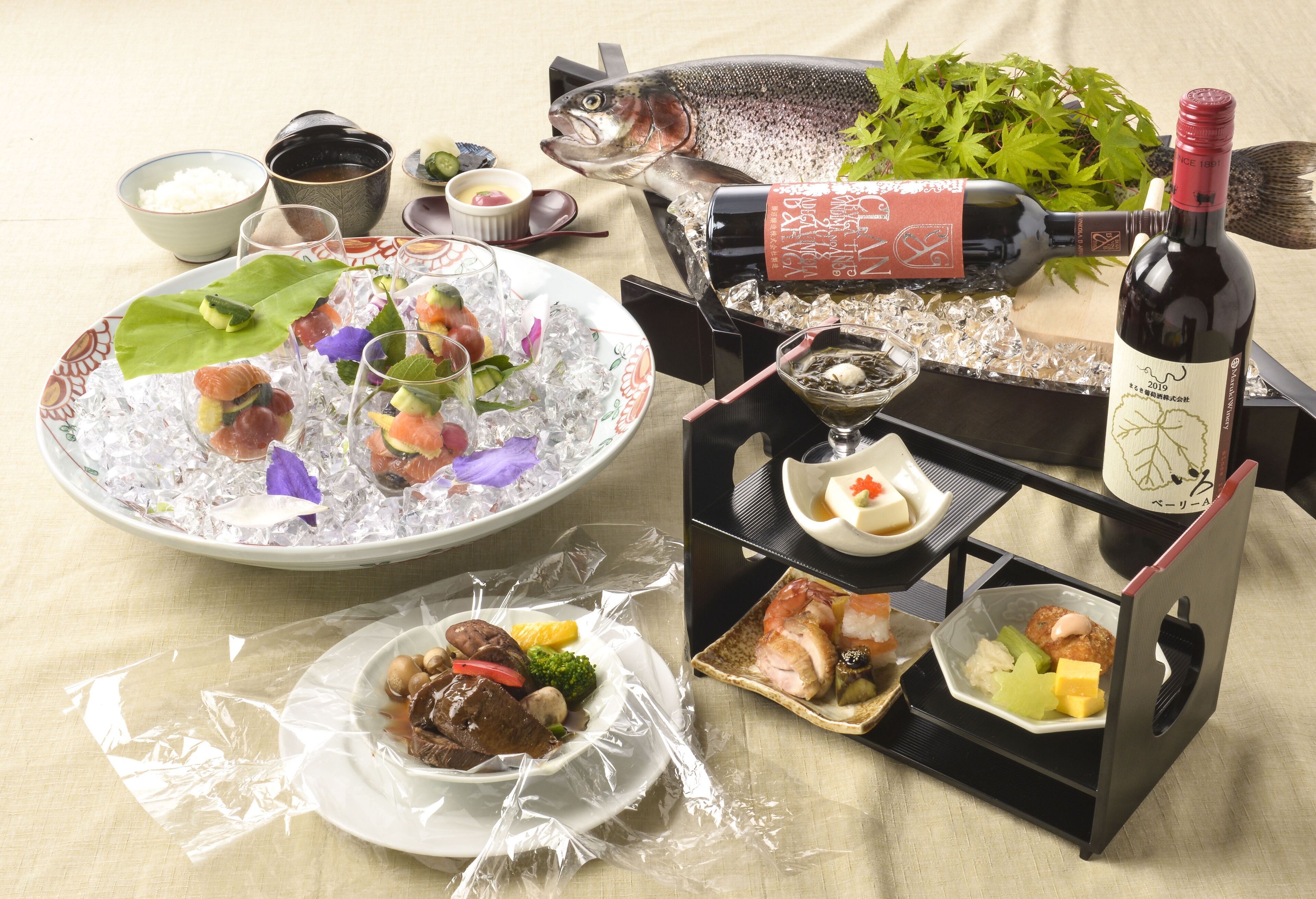 Une table dressée avec différents plats, notamment des sushis, des sashimis et une bouteille de vin.