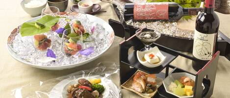 A table set with various dishes, including sushi, sashimi, and a bottle of wine.