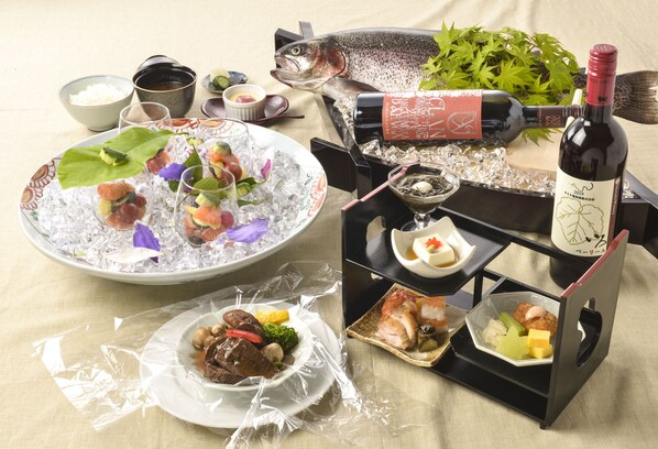 A table set with various dishes, including sushi, sashimi, and a bottle of wine.