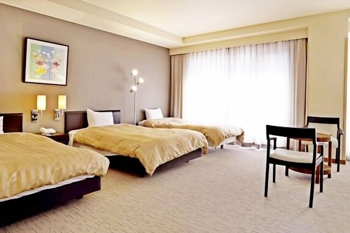 Habitación de hotel con dos camas, un escritorio y una silla.