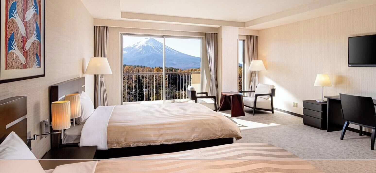 Een hotelkamer met een groot bed, twee nachtkastjes met lampen, een bureau met stoel en een televisie.