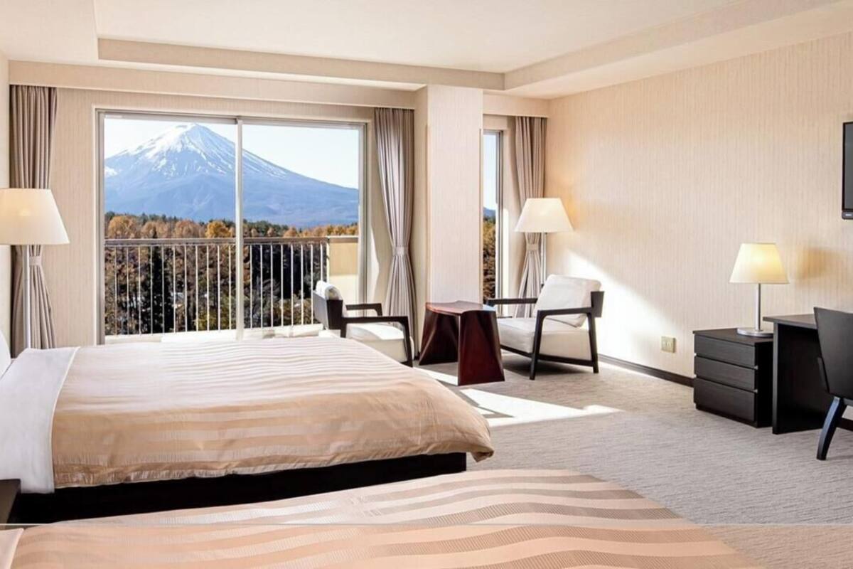 Habitación de hotel con una cama grande, dos mesitas de noche con lámparas, un escritorio con silla y un televisor.