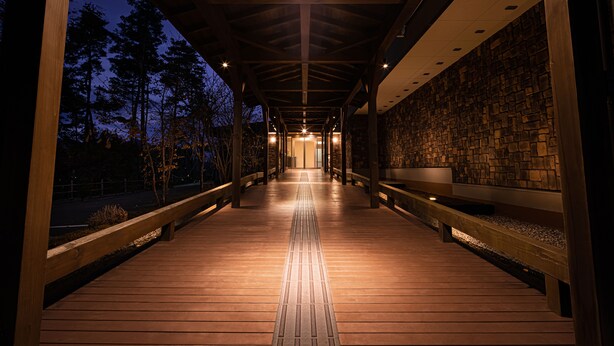 A covered wooden walkway with benches and a stone wall on one side. - The Gran Resort Princess Fujikawaguchiko (Fujikawaguchiko)